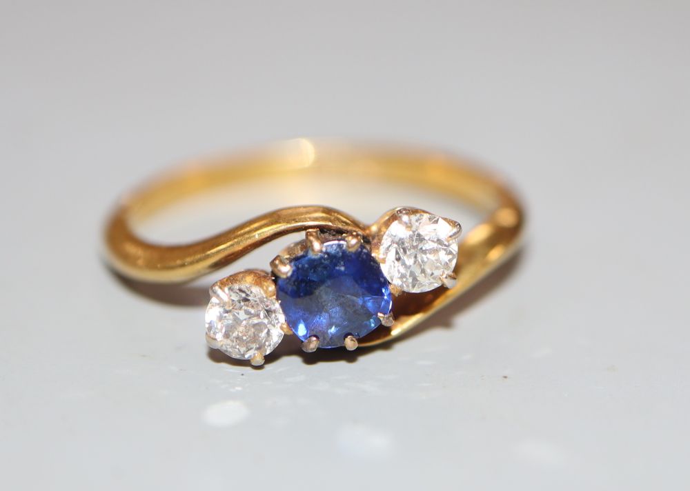 An 18ct, sapphire and diamond set threes stone crossover ring, size L/M, gross 2.4 grams.